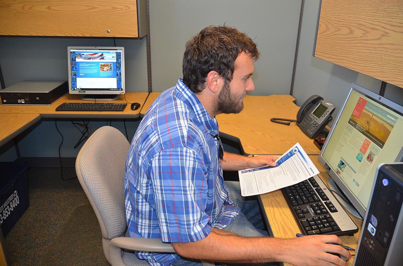 Office worker at a desk with a laptop and monitor in a branch office