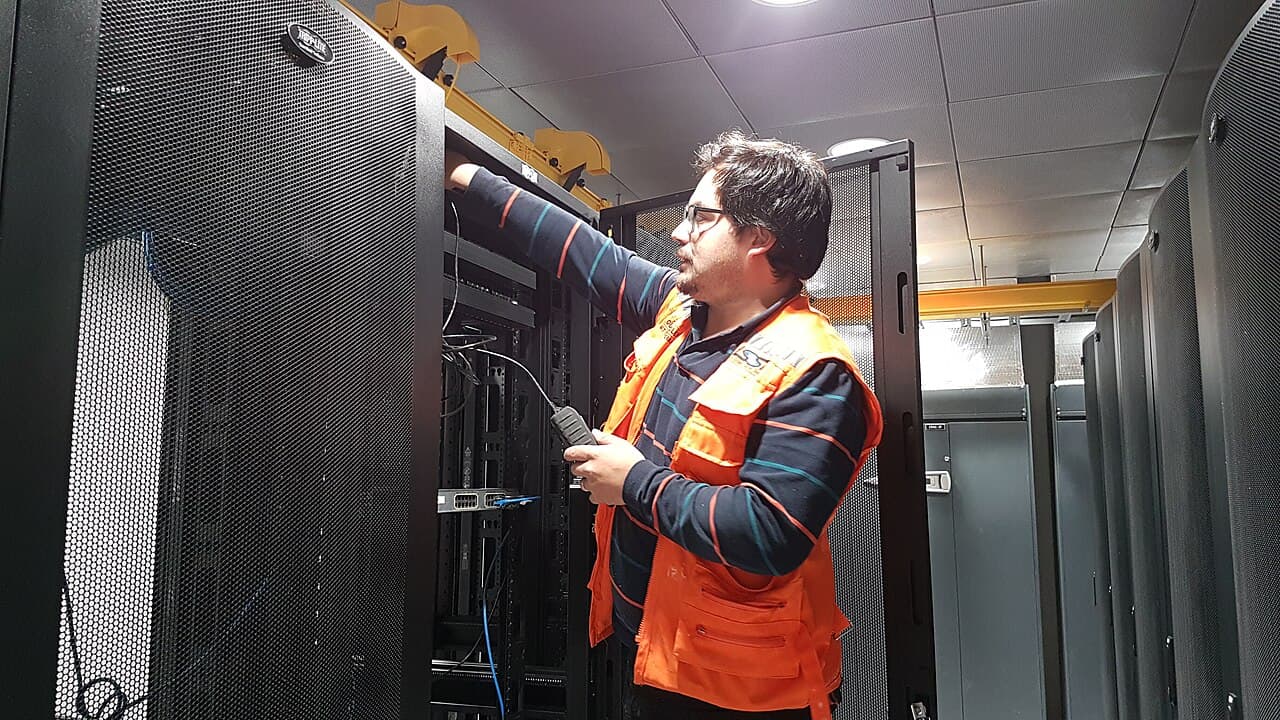 Field engineer in a hi-vis vest servicing equipment in a server room